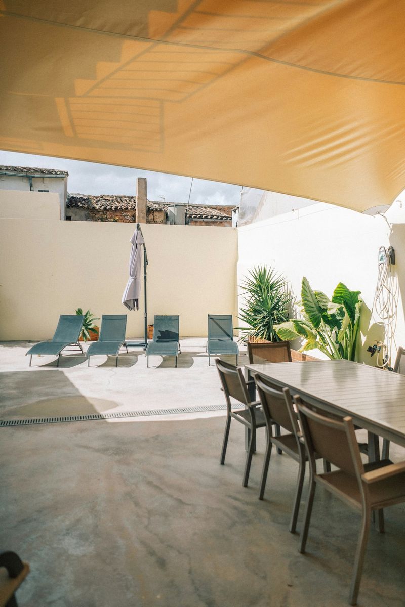 Aluminum pergola frame assembled over a backyard patio behind a modern house
