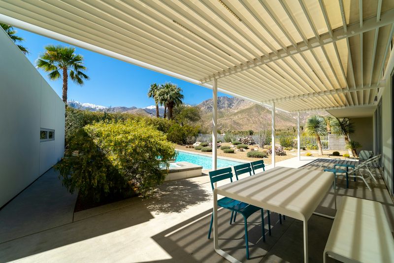 Freestanding aluminum louvered pergola covering a patio dining set with the motorized slats angled part-open