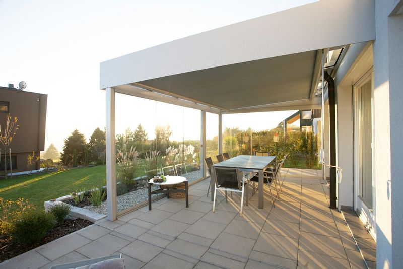 Aluminum louvered pergola shading an outdoor dining set on a lawn