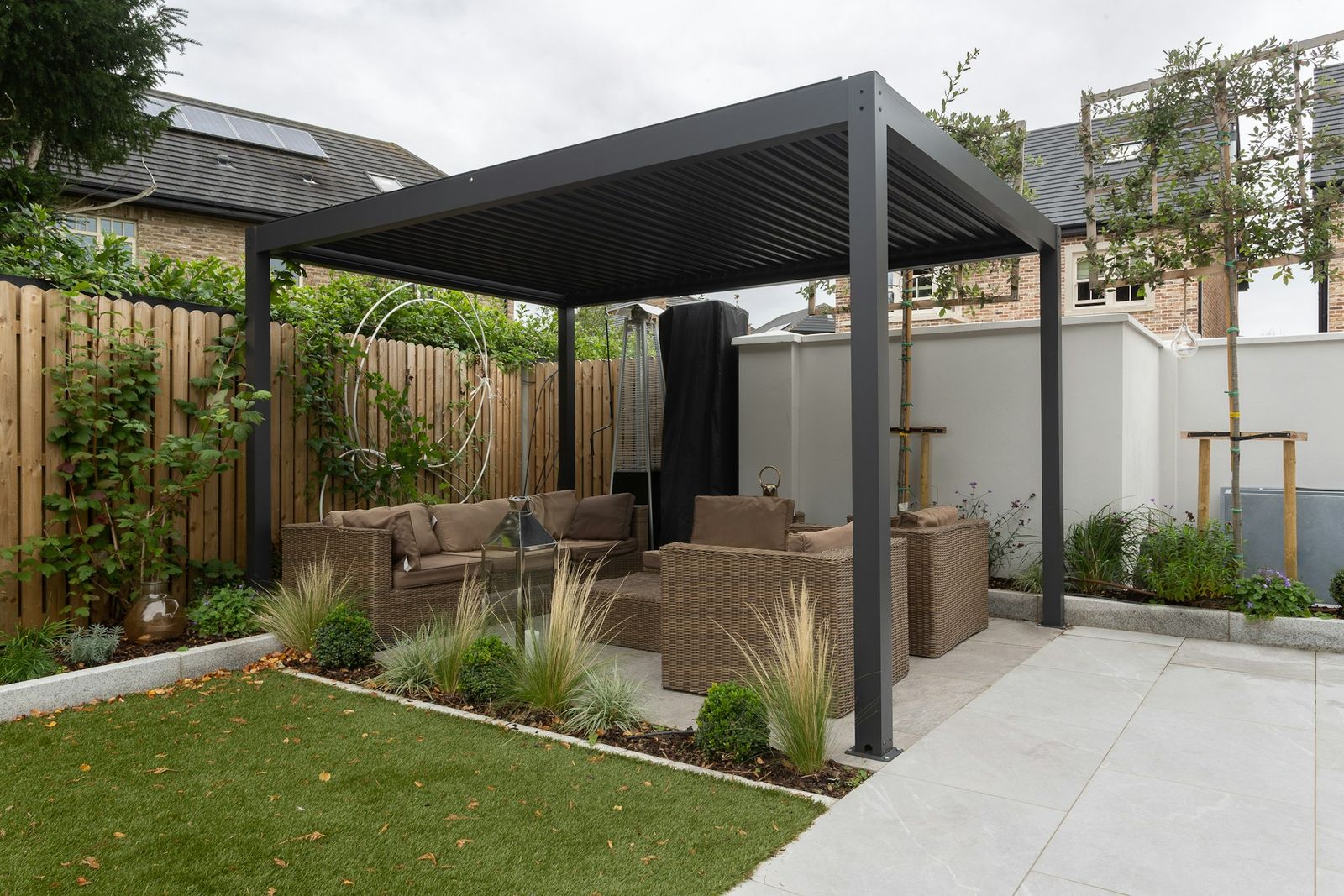 Freestanding dark aluminum automatic louvered pergola with the slat roof closed over a backyard patio seating area