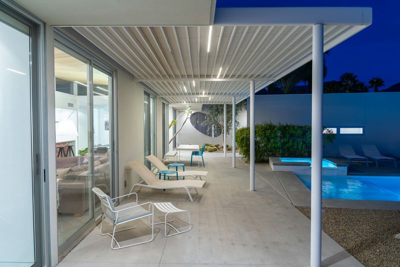 Aluminum pergola structure lit at night beside a pool on an exposed coastal property