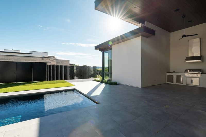 Large louvered pergola structure shading an outdoor kitchen and pool deck