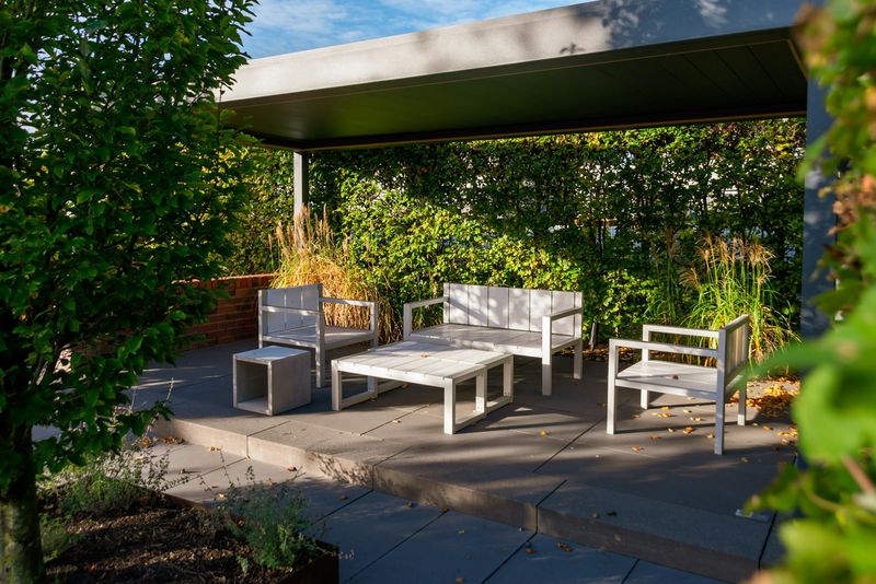 Compact aluminum pergola shading a white outdoor sofa and coffee table